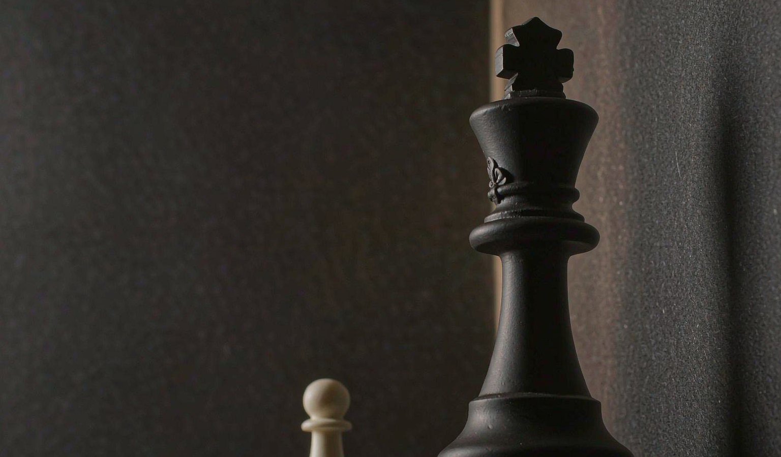 暗调画面中一枚高大的黑色棋王与左侧小小白兵，寓意量级差异